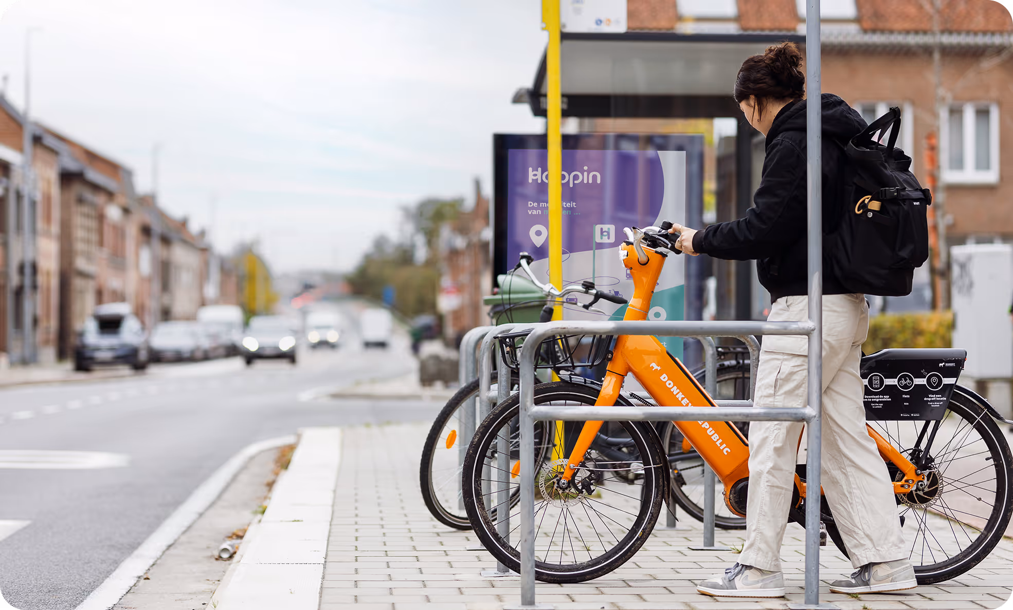 A person standing next to a bike on a street.